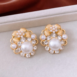 Detailed close-up of vintage gold flower earrings with white pearls and crystals