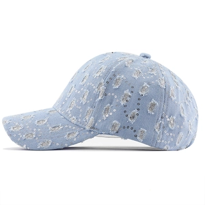 Detail of distressed light blue denim baseball cap with silver sequins and ripped design