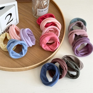 Close-up of soft seamless elastic hair ties in various colors on a wooden tray