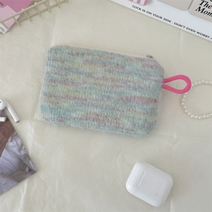 Detail of colorful knit plush storage bag with zipper and handle on a textured background