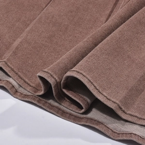 Détail de la texture denim marron avec des coutures de précision sur l'ourlet de la robe