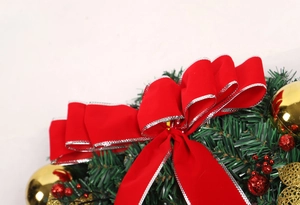 Close-up of Christmas wreath with red velvet bow, gold ornaments, and pine needles