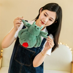 Green plush spider toy with red spots being placed into a denim overall pocket