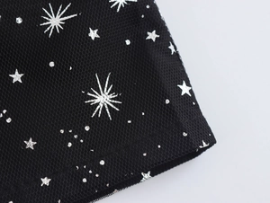 Dettaglio del tessuto a rete nero con motivi di stelle e punti argento scintillanti
