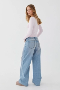 Détail du jean large à taille haute délavé avec poches arrière et coupe fluide élégante