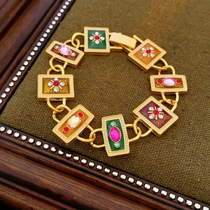 Macro shot of vintage gold bracelet with colorful enamel floral and bow details