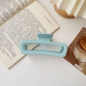 Dettaglio di una pinza per capelli blu opaco con design rettangolare su un libro