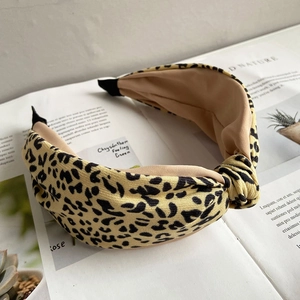 Detail of knot design on leopard print fabric headband placed on a vintage magazine