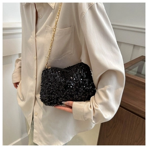 Fashionable black sequin chain bag worn by a model in a beige shirt as a chic shoulder bag