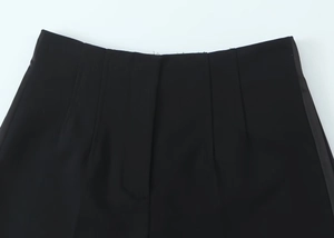 Dettaglio ravvicinato dei pantaloncini neri a vita alta con focus su cintura e pieghe