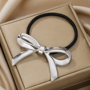 Minimalist silver metal bow hair tie with elastic band on a luxury silk background
