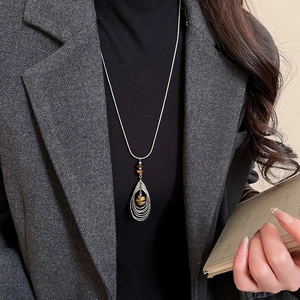 Detailed view of long layered necklace with tiger eye beads on silver chain sweater jewelry