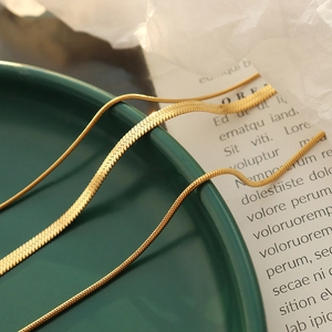 Three-layer golden snake bone necklace set on a dark green decorative plate
