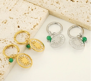 Detailed view of sunburst charm hoop earrings in gold and silver with turquoise beads