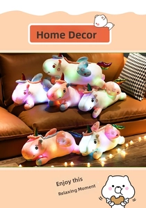 Luminous unicorn plush pillows stacked on a brown sofa with ambient string lights.