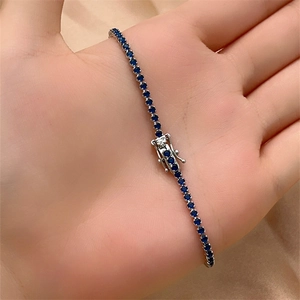 Detailed macro view of a tennis bracelet with blue zircons and secure box clasp closure