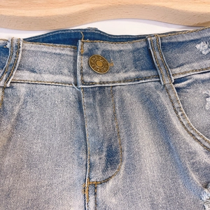 Dettaglio vita degli shorts in denim azzurro con bottone in rame e trama del tessuto