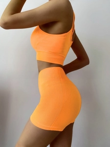 Detail of neon orange seamless yoga set with ribbed texture and racerback sports bra