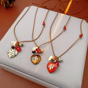 Detailed view of heart-shaped stone pendants with silver cross on wax cord necklaces