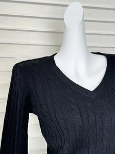 Close-up of black cable knit sweater featuring a V-neck design and slim fit on a mannequin