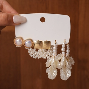 Close-up of pearl earrings and white flower petal tassel earrings set in gold
