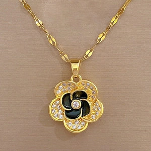 Macro-opname van gouden bloemenhanger met zwart emaille en micro-gepaveerde kristallen