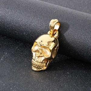 Macro close-up of a gold skull pendant showing detailed gothic metal texture on black surface