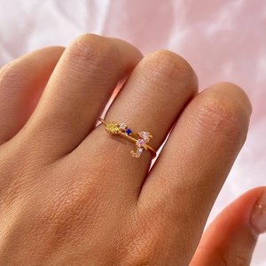 Macro shot of a gold ocean ring featuring a delicate shell and colorful zircon stones