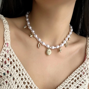 Detail of a pearl necklace with gold shell and starfish pendants on a model's neck