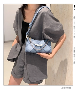 Dettaglio della borsa a mezzaluna in denim trapuntato con perle bianche e catena dorata