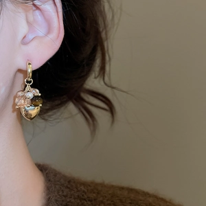 Close-up of heart charm and beaded tassel earrings on model showing retro gold details
