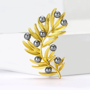 Exquisite golden olive branch leaf brooch with grey pearls on minimalist background
