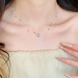 Close-up of double-layer necklace featuring a clear round pendant and pearl accents