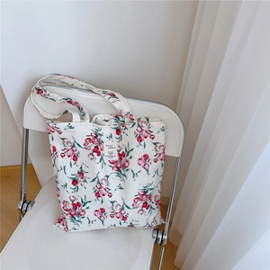 Detail of floral canvas tote bag with red tulips resting on a minimalist chair