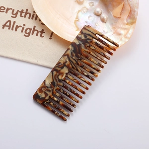 Macro view of wide-tooth acetate hair comb with tortoise shell pattern and cloth bag