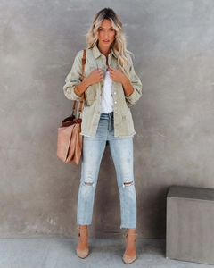 Detail of light green distressed denim jacket with frayed edges and ripped texture