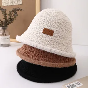 Three plush bucket hats in white, brown, and black with leather handmade labels