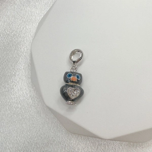 Detail view of a S925 silver owl charm with dark grey enamel and rhinestone heart inlay