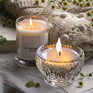Detail shot of faceted glass candle cups with embossed patterns on warm cozy blankets