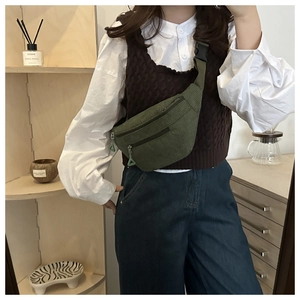 Detail of green corduroy crescent waist bag with adjustable strap worn by a model