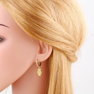 Close-up of owl drop earrings in gold finish with sparkling rhinestones on model