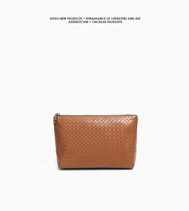 Detail of a brown woven leather tote with cross-weave texture and golden zipper