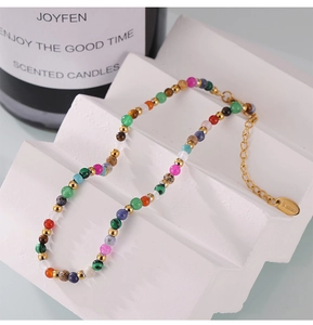 Macro detail of a colorful beaded anklet with S.Steel engraved tag and gold chain