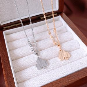 Close-up of gold and silver clover pendants with textured grid pattern on velvet