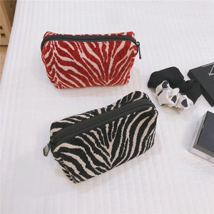 Detailed close-up of two boat-shaped zebra print velvet makeup bags with metal zippers
