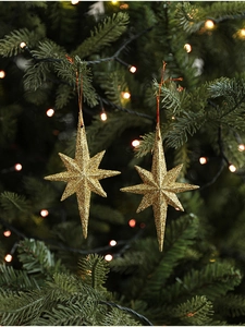 Detail of a gold glittered eight-pointed star ornament hanging on a Christmas tree