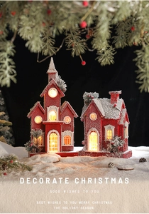 Close-up of red wooden Christmas house with LED warm glow and artificial snow decor