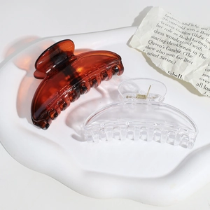 Semi-circular hair claw clips in amber and transparent finish on a white tray