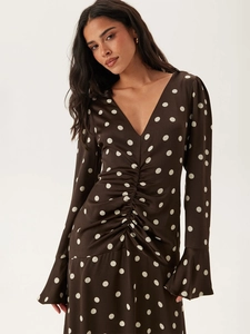 Détail du col en V et du design froncé sur cette robe en satin marron à pois