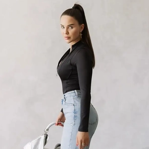Detail view of a black slim-fit long-sleeved bodysuit paired with light blue high-waisted jeans